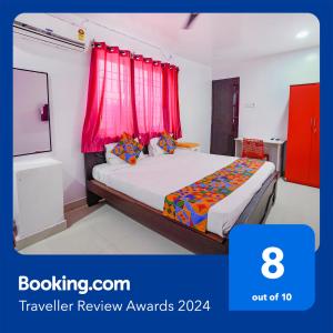 um quarto com uma cama com cortinas vermelhas e uma televisão em FabExpress Lloyds Inn I em Chennai