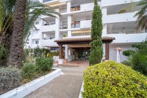 a large white building with palm trees and bushes at Apartamento ROYAL MARINE in Empuriabrava