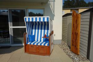 einem blauen und weißen Stuhl auf einer Terrasse in der Unterkunft Küstenwald - Ferienwohnung Igelring H in Müritz