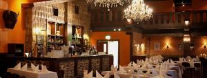 a restaurant with white tables and a bar with chandeliers at Himos Villi Cottages in Jämsä