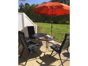 a table with a red umbrella on a patio at Küstenwald - Ferienwohnung Seeigel in Müritz