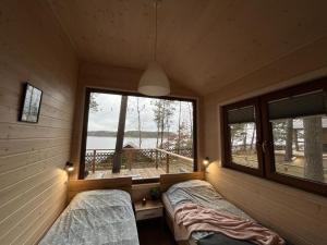 two beds in a room with a window at WYPOCZYWANKO DOMEK PIERWSZA LINIA BRZEGOWA in Borsk