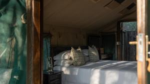 una camera da letto con un letto con cuscini sopra di Mashatu Tent Camp a Lentswelemoriti