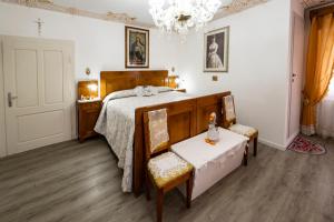 a bedroom with a bed and two chairs and a chandelier at Palazzo Cervesato: Camera Regina Margherita in Santo Stefano di Cadore
