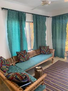 un sofá en una sala de estar con cortinas verdes en Sand Beach Boutique Villas, en Bwejuu