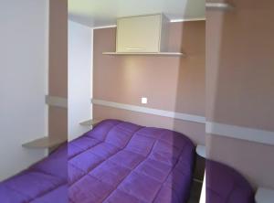 a purple bed in a room with a purple blanket at Mobil Home 6 personnes 206 in Mens