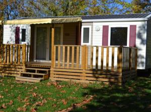 ein winziges Haus mit einer Veranda und einem Zaun in der Unterkunft Mobil Home 6 personnes 206 in Mens