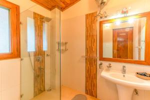 a bathroom with a shower and a sink and a mirror at StayVista at The Woods in Chail