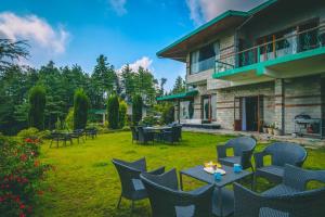 a yard with tables and chairs and a building at StayVista at The Woods in Chail