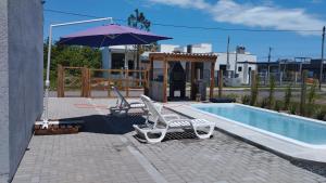 two lounge chairs and an umbrella next to a swimming pool at Morada do bosque in Capão da Canoa