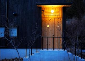 a wooden door of a house with a light on it at とけとけ山荘 in Fujikawaguchiko