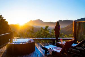 uma mulher de pé num deque com uma banheira de hidromassagem em Maua Brasil Hotelaria em Visconde de Mauá