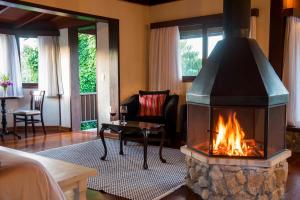 chimenea en una habitación con sofá y silla en Maua Brasil Hotelaria, en Visconde De Maua