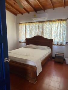 Schlafzimmer mit einem Bett mit einem Kopfteil aus Holz und einem Fenster in der Unterkunft Cabaña Coveñas Los García in Coveñas