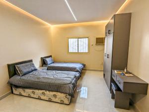 a room with two beds and a desk in it at Madina Luxe Apartments - 7 minutes to Haram by Car - Mount Uhud Views - Free Parking - Kitchen in Al Madinah