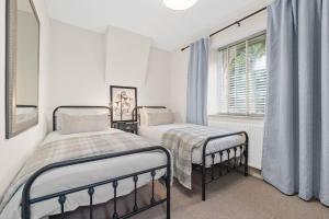 a white bedroom with two beds and a window at Quintessential Apartment, The Coach house in Blockley
