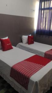 2 camas con almohadas rojas en una habitación en HOTEL CYSNE, en Sobral