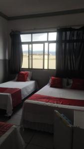 two beds in a room with a window at HOTEL CYSNE in Sobral