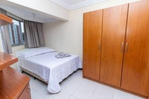 1 dormitorio con 1 cama y armario de madera en Ap Balneário Camboriú - Próximo Roda Gigante, en Balneário Camboriú