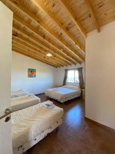 1 dormitorio con 2 camas y techo de madera en Todos Los Glaciares en El Calafate