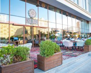 um restaurante com mesas e cadeiras em frente a um edifício em Park azure sweet apartment by Baku Housing em Baku