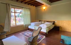 a bedroom with a bed and two chairs and a window at Namkha Homestay by StayApart in Tabo