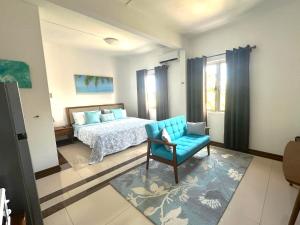 a bedroom with a bed and a blue chair at Residence Le Point Choisy in Pointe aux Canonniers
