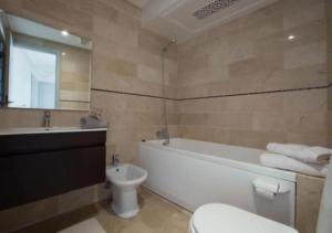 a bathroom with a tub and a toilet and a sink at Superbe appartement à la corniche de Casablanca in Casablanca