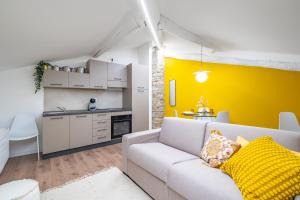 a living room with a couch and a yellow accent wall at Cascina Conicchio - Metro Station - by Host4U in Brescia
