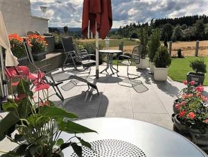 eine Terrasse mit einem Tisch, Stühlen und Blumen in der Unterkunft Haus Ketterer in Bad Dürrheim