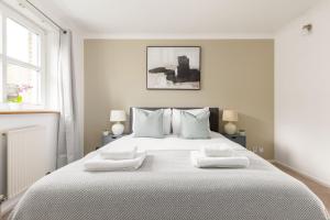 een witte slaapkamer met een groot wit bed met 2 kussens bij The Canada Water Apartments in Londen