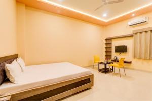 een slaapkamer met een bed, een bureau en een televisie bij OYO Hotel Ambika Palace in Patna