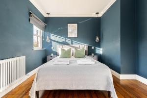 a blue bedroom with a large bed with green pillows at The Putney Villa in London