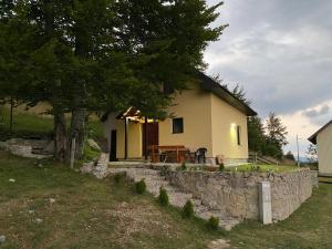 a small house with a stone wall next to a tree at Lasica in Žabljak