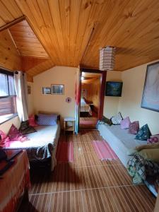 a room with two beds and a wooden ceiling at Casa Dell Angelo Apartamentos in Visconde De Maua