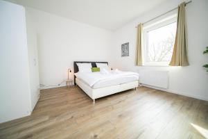 a white bedroom with a bed and a window at Deluxe Apartments - 1 & 2 Bedroom - Zentral - 10 Min Messe in Düsseldorf