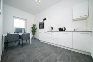 a kitchen with white cabinets and a table with chairs at Deluxe Apartments - 1 & 2 Bedroom - Zentral - 10 Min Messe in Düsseldorf