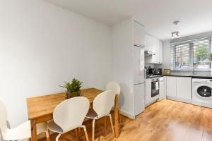 a kitchen with a wooden table and white chairs at 1 Bed Garden Flat in Belsize Park next to station! in London