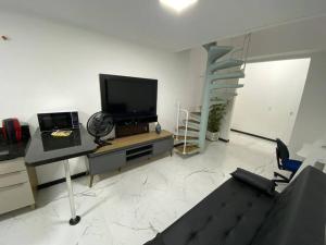 a living room with a flat screen tv and a staircase at Loft no Espinheiros - Joinville/SC in Joinville