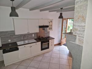 a kitchen with white cabinets and a stove top oven at Gite les Frênes avec pré dans joli hameau in Vermenton