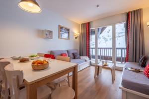 a kitchen and living room with a table and a couch at Résidence Pierre & Vacances Le Thabor in Valmeinier