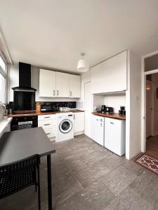 uma cozinha com armários brancos e uma mesa em Penny's Place in Grove Park em Eltham