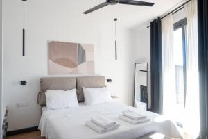 1 dormitorio blanco con 1 cama con 2 toallas en Χαλάρωση με στυλ στο κέντρο Αγίων Θεοδώρων, en Agioi Theodoroi