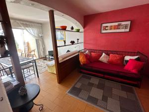 ein Wohnzimmer mit einer roten Wand und einem Sofa in der Unterkunft Grand T2 avec loggia et terrasse à proximité du port de Saint Mandrier et des plages in Saint-Mandrier-sur-Mer