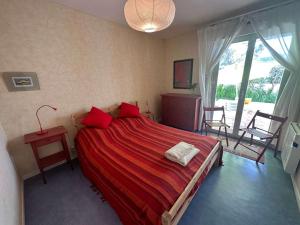 ein Schlafzimmer mit einem großen Bett mit roter Bettwäsche in der Unterkunft Grand T2 avec loggia et terrasse à proximité du port de Saint Mandrier et des plages in Saint-Mandrier-sur-Mer