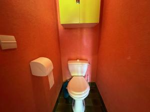 ein kleines Bad mit einem WC in einer orangefarbenen Wand in der Unterkunft Grand T2 avec loggia et terrasse à proximité du port de Saint Mandrier et des plages in Saint-Mandrier-sur-Mer