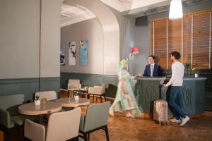 two people with luggage standing at a counter in a restaurant at Hôtel Vendôme Menton in Menton