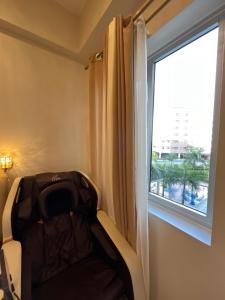 um quarto com uma cadeira e uma janela em PECHO PERFECT SUITE WITH MASSAGE CHAIR em Cavite