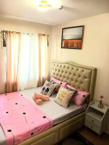 een slaapkamer met een bed met roze lakens en kussens bij Entire 2BR condo 8 Spatial Maa Davao in Davao City