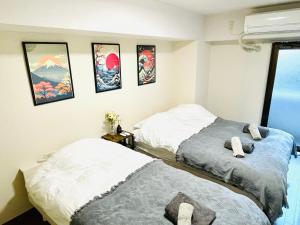 two beds in a room with pictures on the wall at Apartment hotel Hana in Yokohama in Yokohama